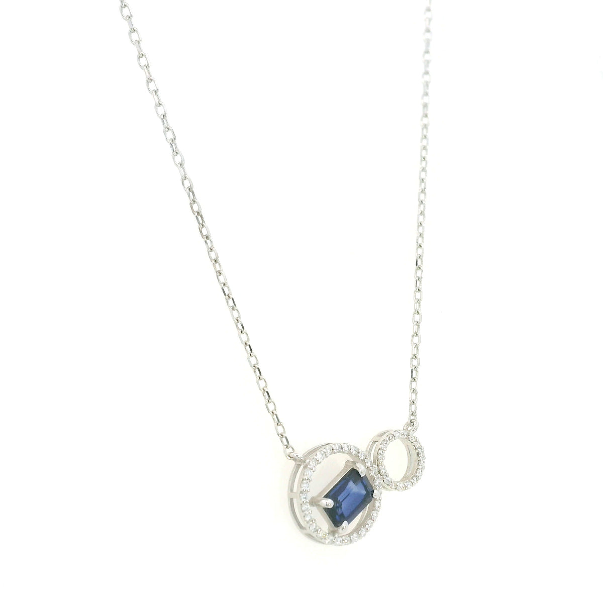 Blue emerald-cut sapphire and diamond necklace in 18K white gold, featuring an asymmetrical double-circle design with round diamond accents.