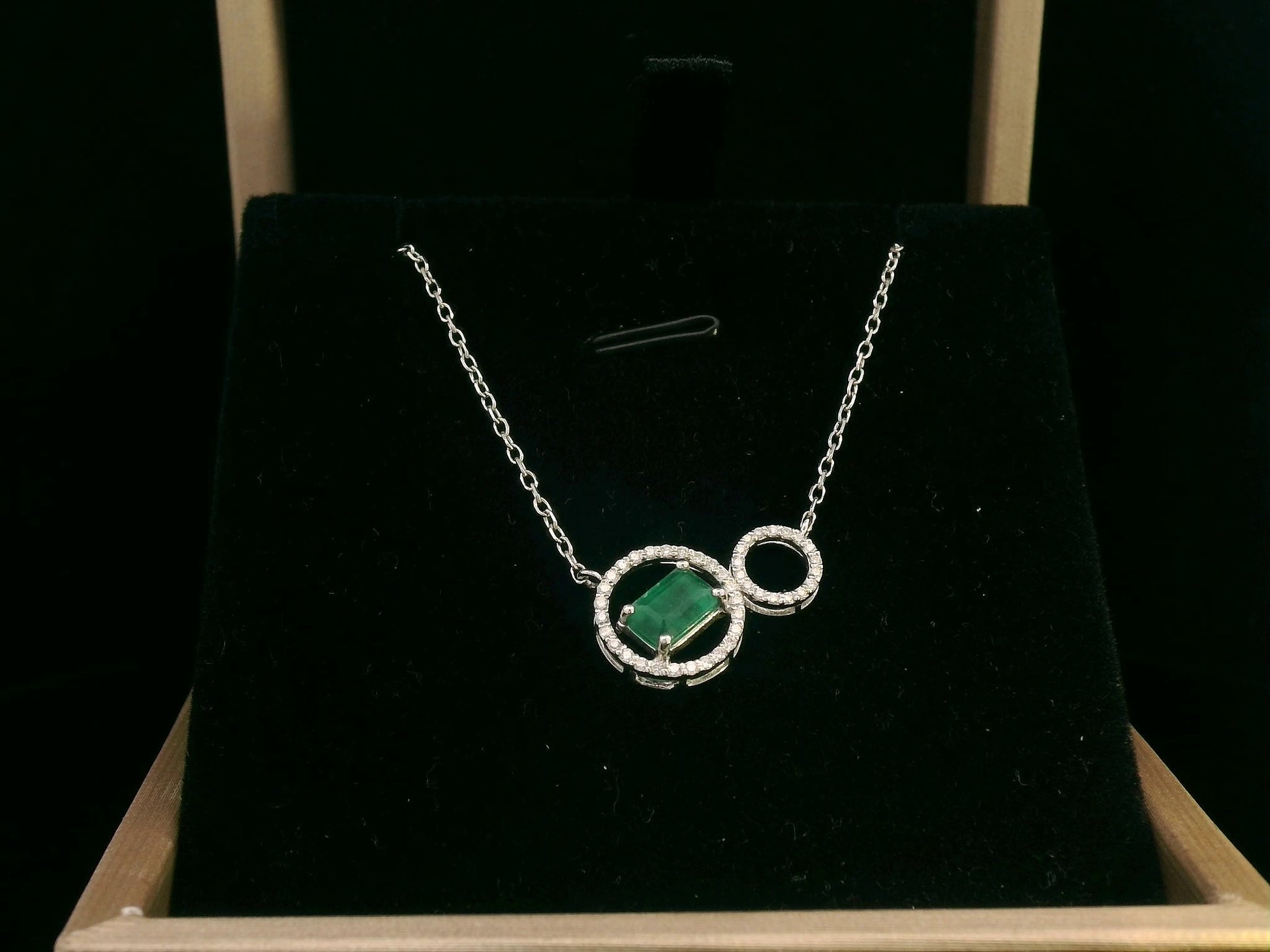 18K white gold necklace featuring a 0.63ct emerald-cut emerald and 0.15ct diamond double-circle pendant, designed for modern elegance and layering versatility