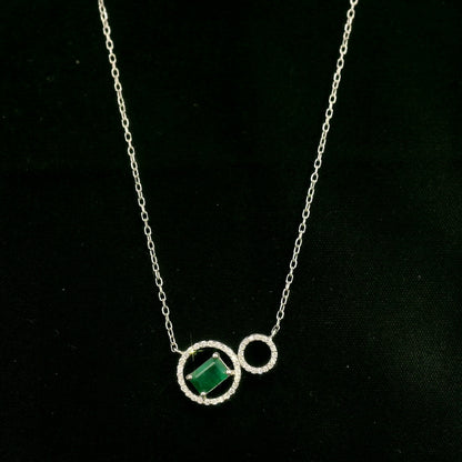 Emerald and diamond necklace in 18K white gold featuring a rectangular emerald-cut green gemstone inside a diamond circle, connected to a smaller diamond-set circle.