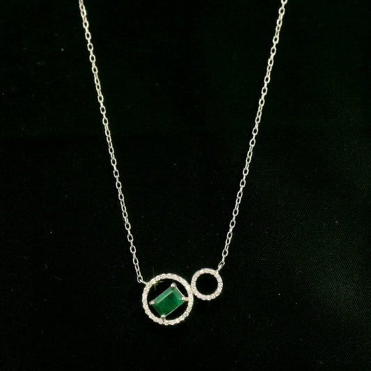 Emerald and diamond necklace in 18K white gold featuring a rectangular emerald-cut green gemstone inside a diamond circle, connected to a smaller diamond-set circle.