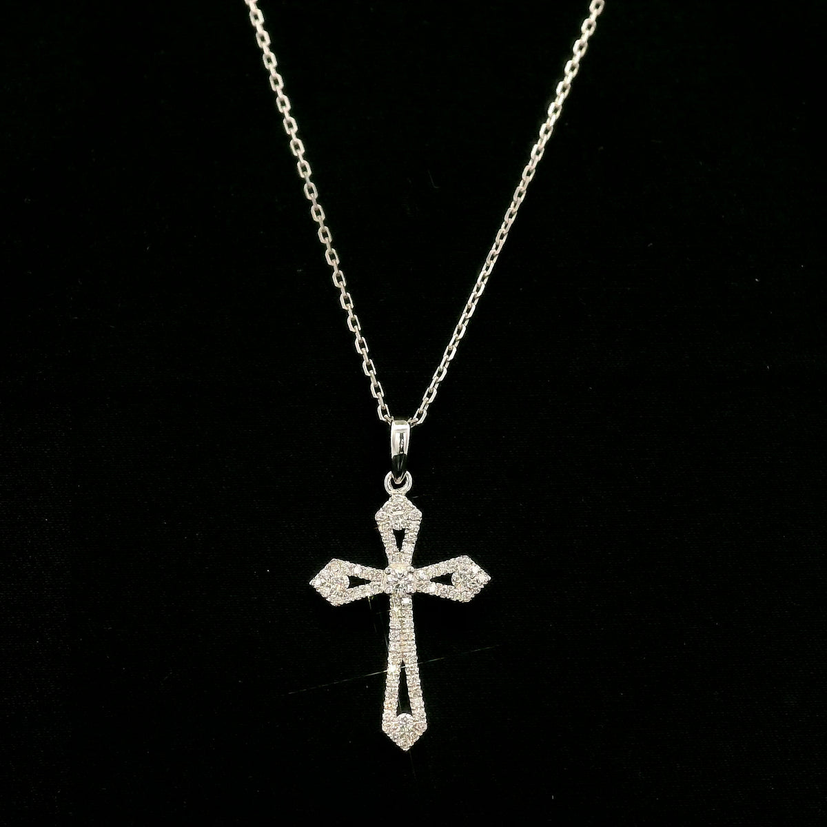 Diamond cross pendant in 18K white gold with round diamonds, an openwork design and distinctive pointed ends.
