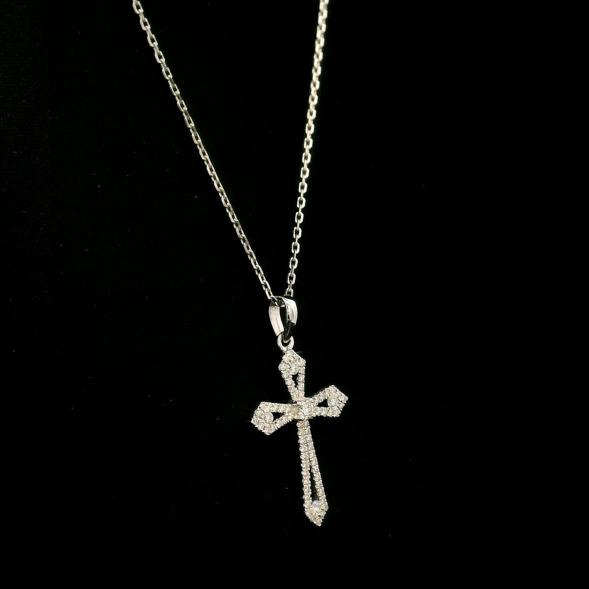 Diamond cross pendant in 18K white gold with round diamonds, an openwork design and distinctive pointed ends.