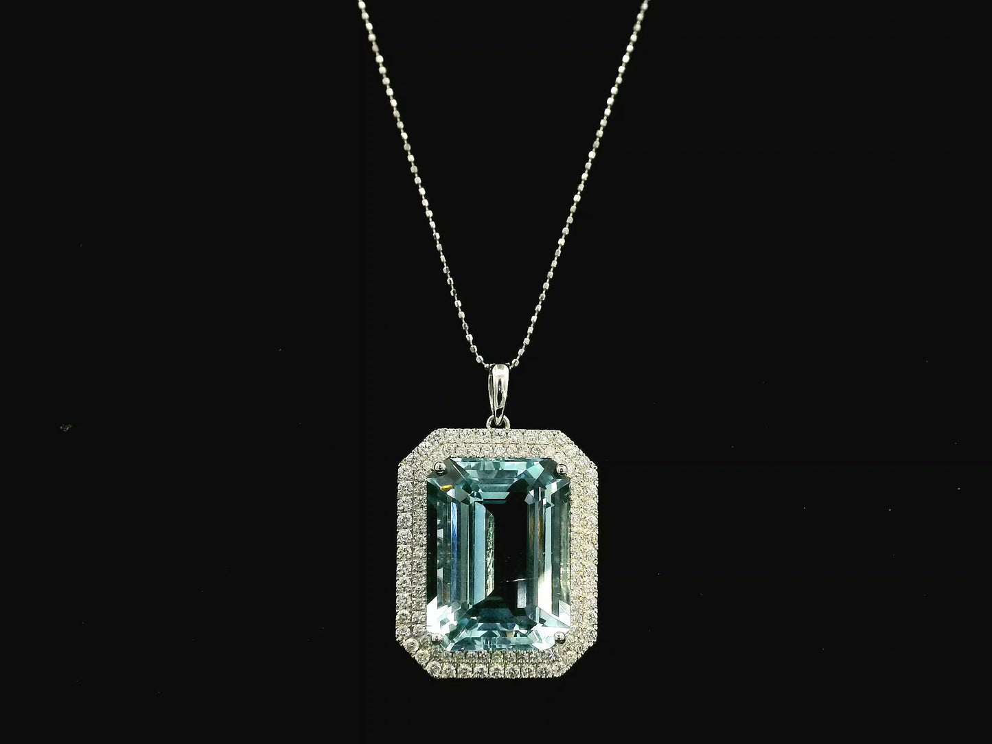 Emerald-cut aquamarine and diamond halo pendant in 18K white gold with large natural aquamarine center stone