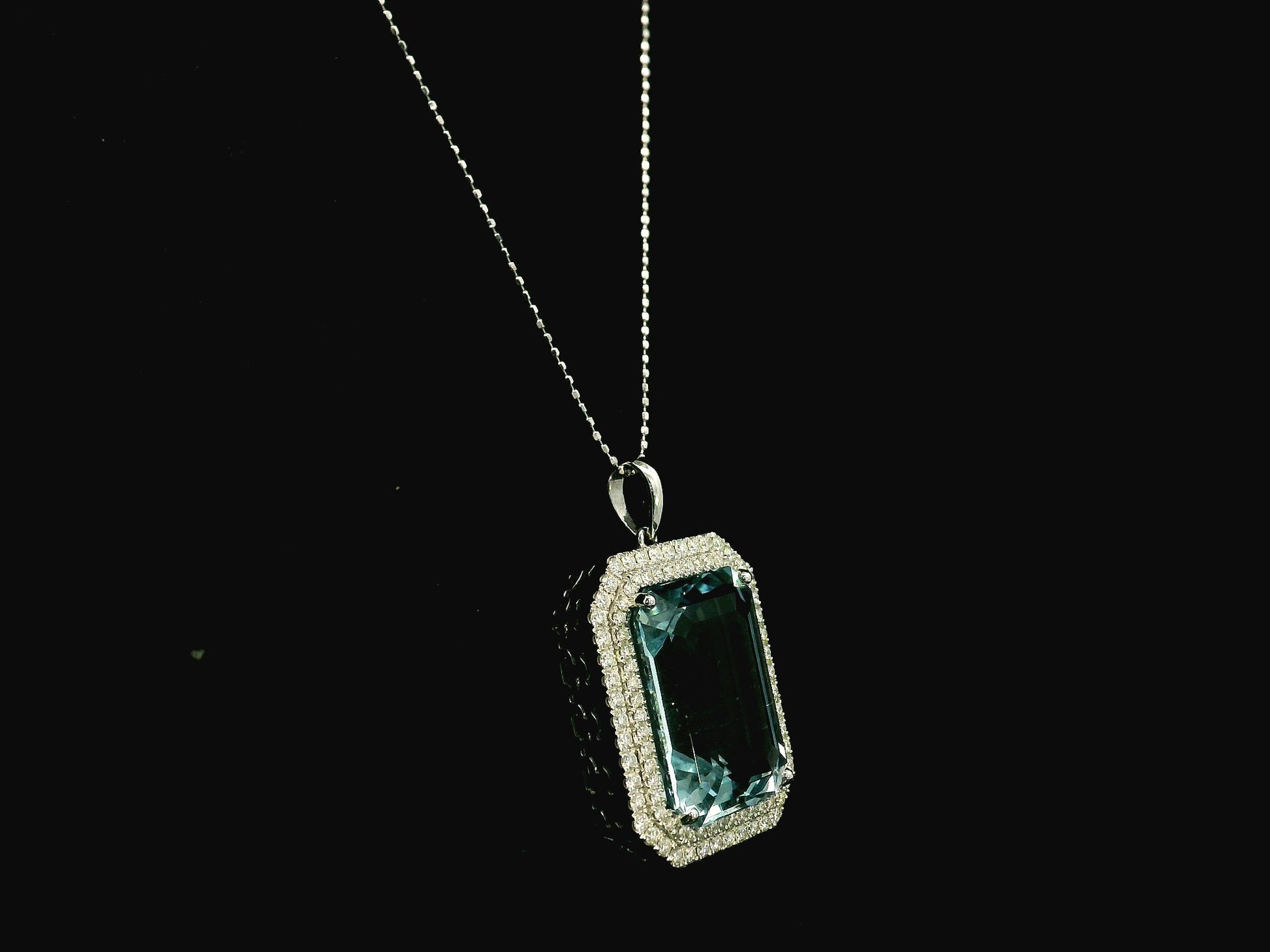 Emerald-cut aquamarine and diamond halo pendant in 18K white gold with large natural aquamarine center stone