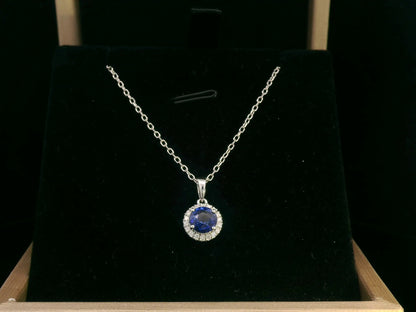 "18K white gold sapphire and diamond halo pendant featuring a 0.72ct deep blue sapphire surrounded by a 0.10ct diamond halo, 