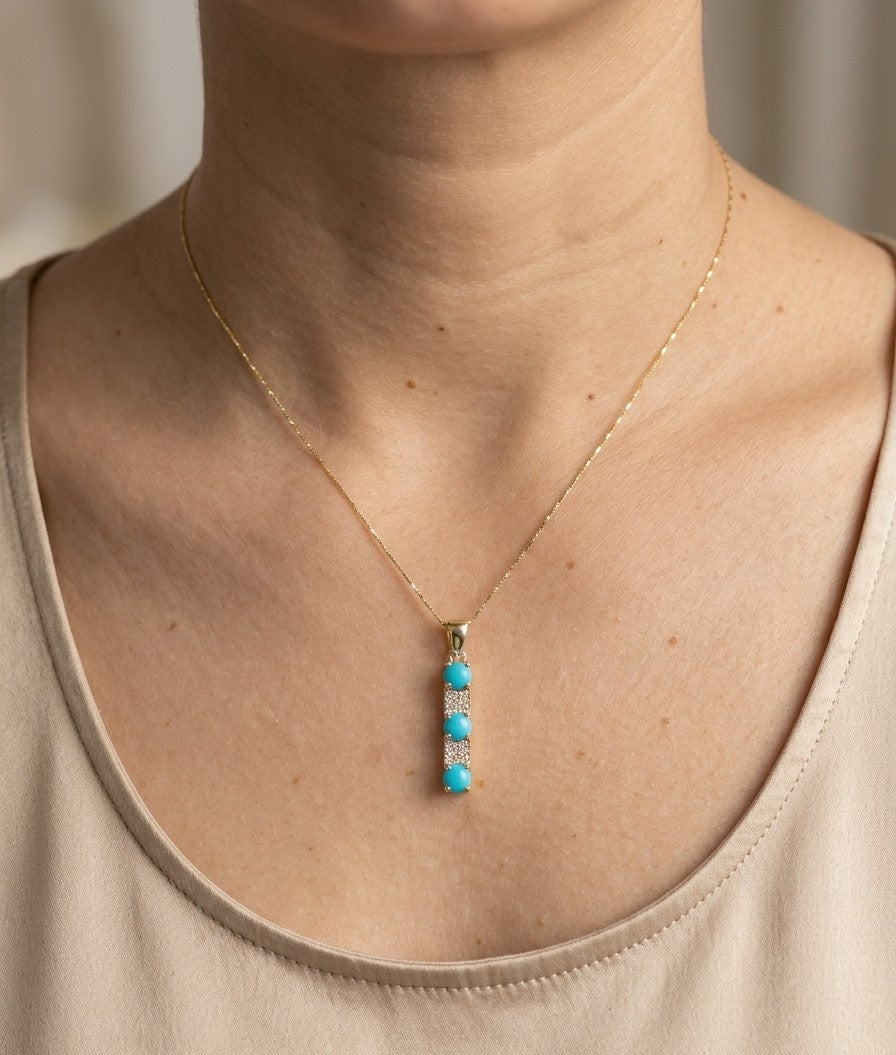Turquoise and diamond drop pendant in 18K yellow gold featuring three round blue turquoise gemstones totalling 0.90 carat, alternating with round diamond accents totalling 0.14 carat. Chain sold separately 