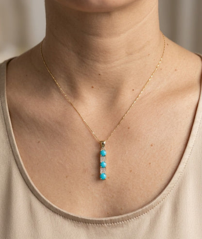Turquoise and diamond drop pendant in 18K yellow gold featuring three round blue turquoise gemstones totalling 0.90 carat, alternating with round diamond accents totalling 0.14 carat. Chain sold separately 