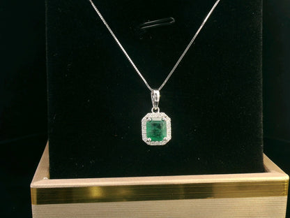 18K gold emerald-cut emerald and diamond halo pendant featuring a 1.12-carat vibrant green emerald with 0.12-carat round diamonds, a timeless fine jewelry piece.