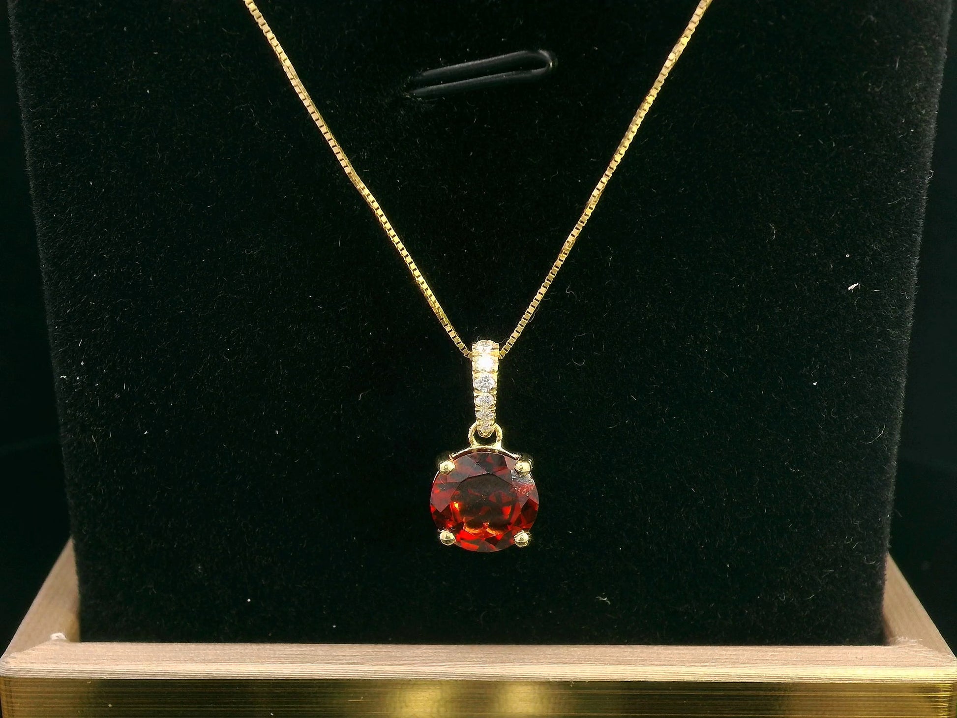 18K gold pendant with a 2.03ct deep red garnet in a four-prong setting, accented by 0.06ct diamonds on the bail. Chain not included.