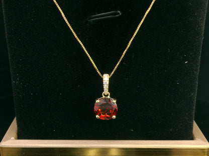 18K gold pendant with a 2.03ct deep red garnet in a four-prong setting, accented by 0.06ct diamonds on the bail. Chain not included.
