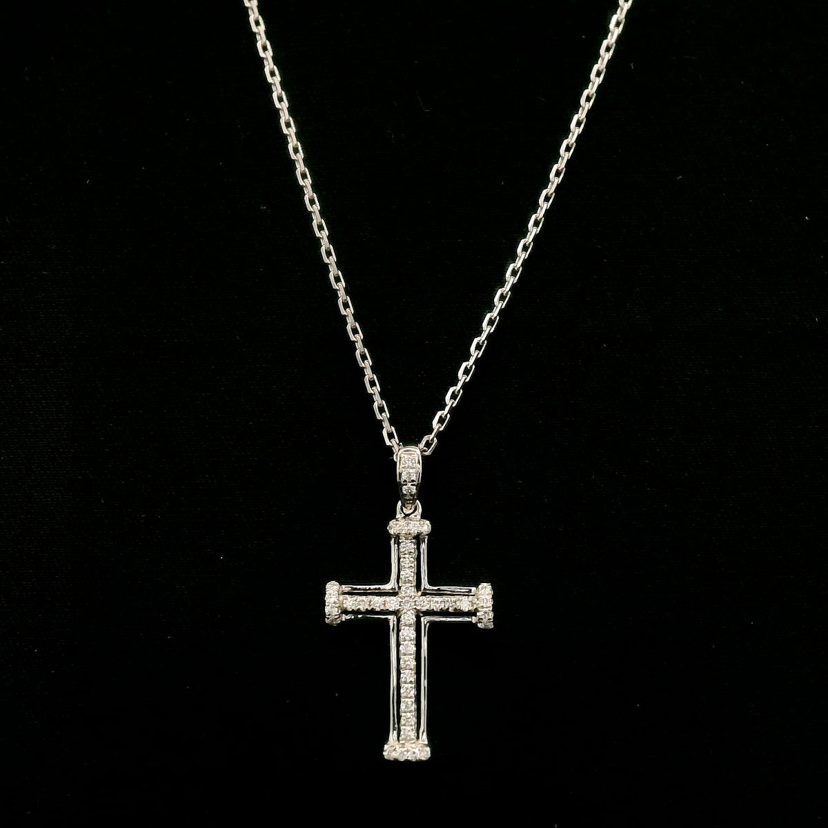 Diamond cross pendant in 18K white gold featuring an openwork design with round diamonds and diamond-accented ends.
