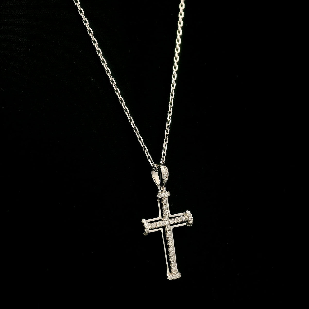 Diamond cross pendant in 18K white gold featuring an openwork design with round diamonds and diamond-accented ends.