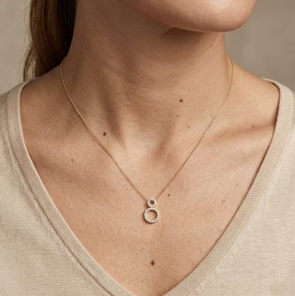 18K yellow gold double open circle pendant necklace featuring 0.18 carat natural round brilliant diamonds in a pavé setting.