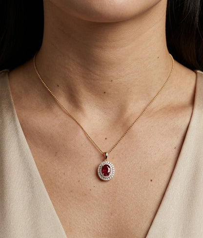 Oval ruby and double diamond halo pendant in 18K yellow gold with a polished gold bail.