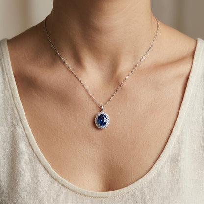 Oval violet-blue tanzanite pendant in 18K white gold surrounded by a double halo of round diamonds.