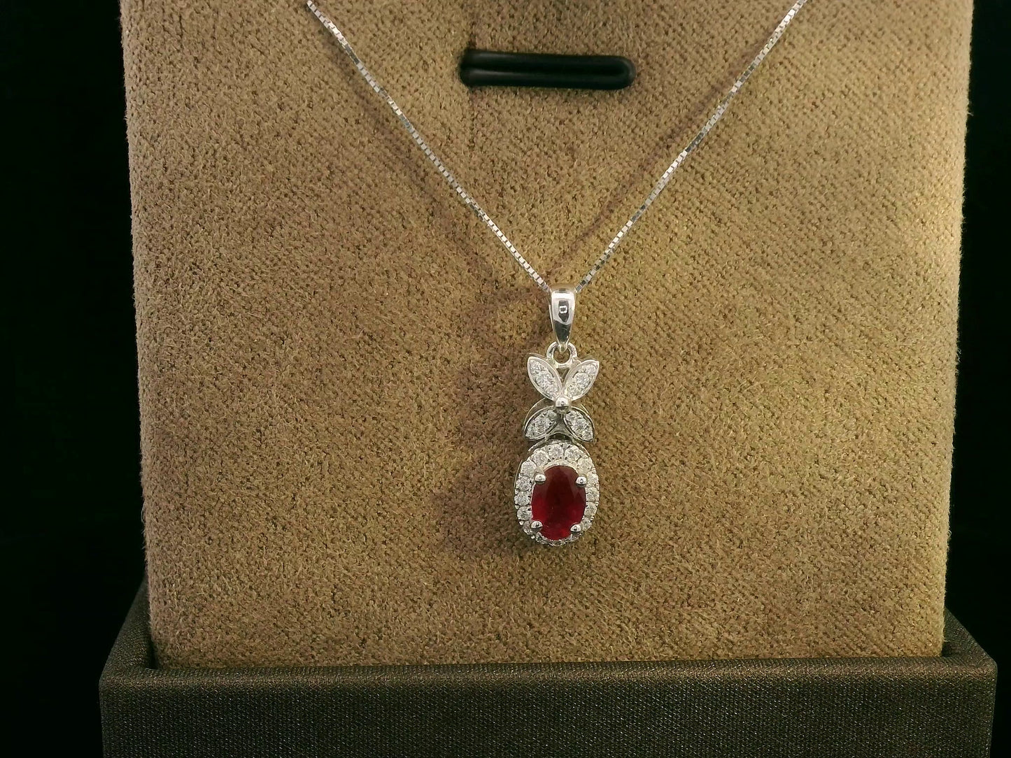 18k white gold pendant with 0.63-carat oval ruby, diamond halo, and floral diamond-accented bail