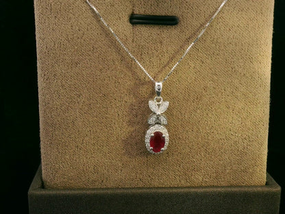 18k white gold pendant with 0.63-carat oval ruby, diamond halo, and floral diamond-accented bail