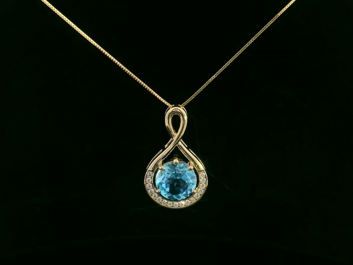 18k yellow gold pendant with 2.30 carat Swiss blue topaz center, diamond halo, and infinity-style bale