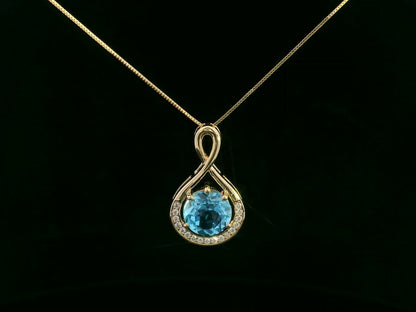 18k yellow gold pendant with 2.30 carat Swiss blue topaz center, diamond halo, and infinity-style bale