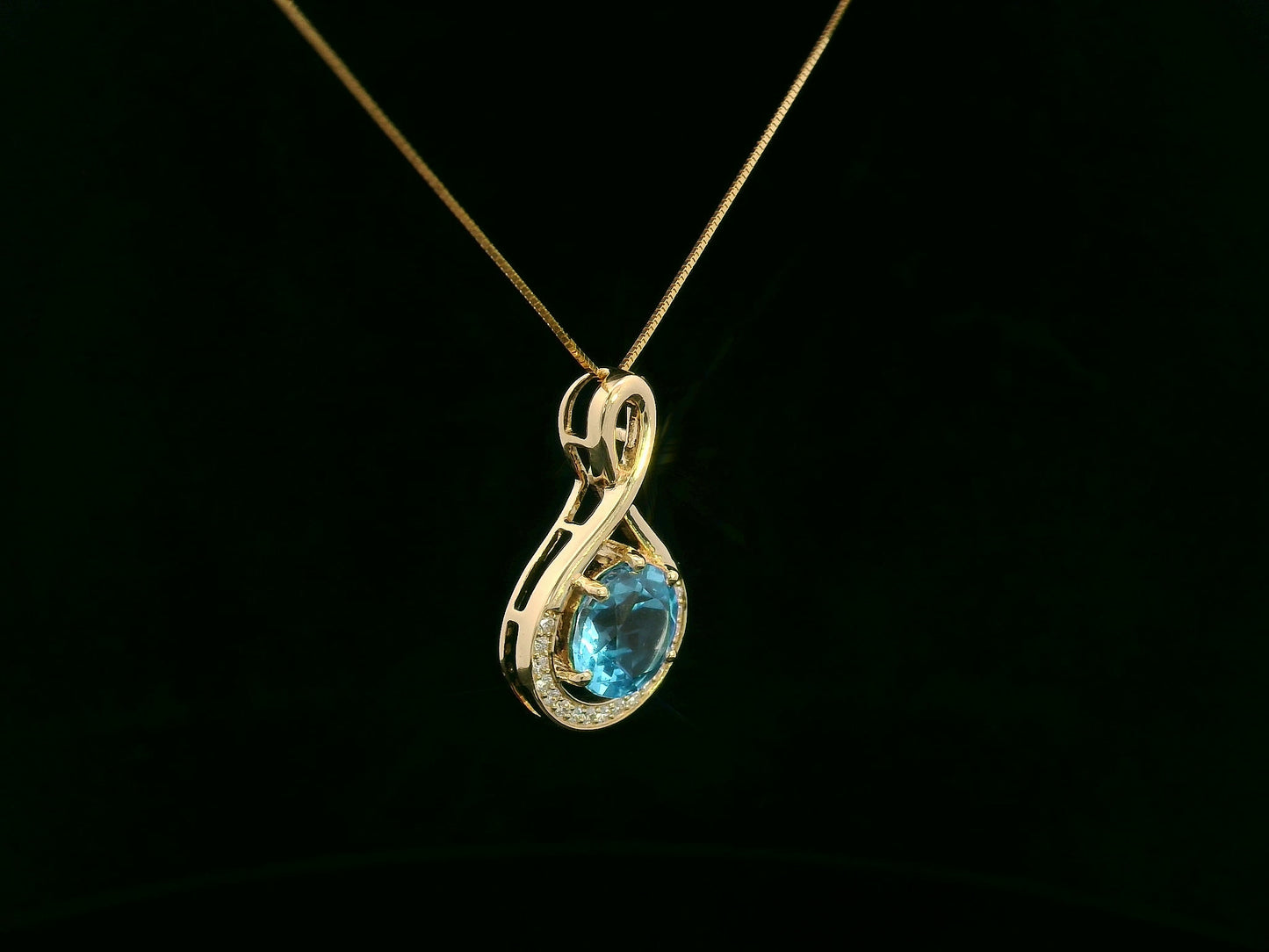 18k yellow gold pendant with 2.30 carat Swiss blue topaz center, diamond halo, and infinity-style bale