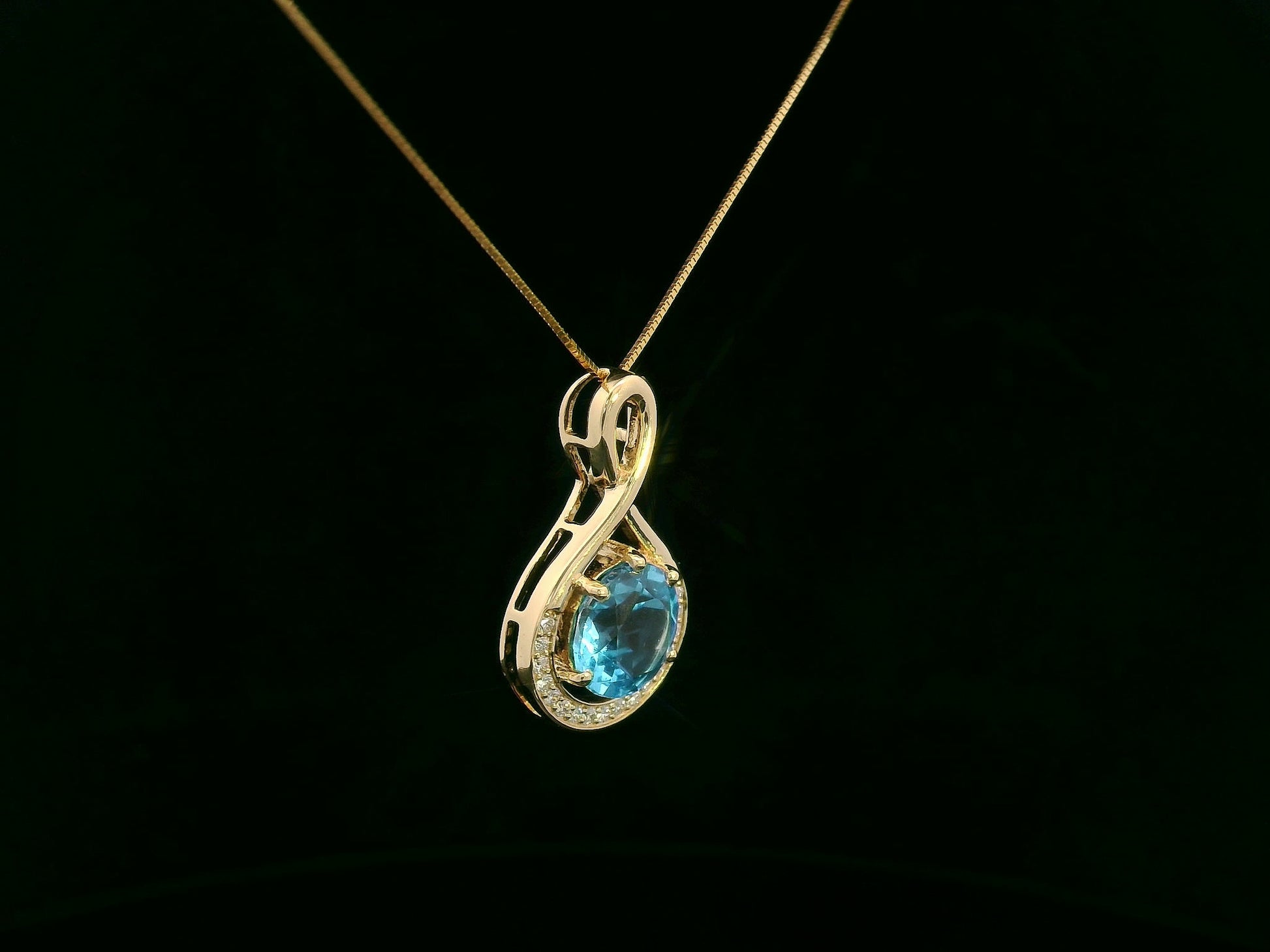 18k yellow gold pendant with 2.30 carat Swiss blue topaz center, diamond halo, and infinity-style bale