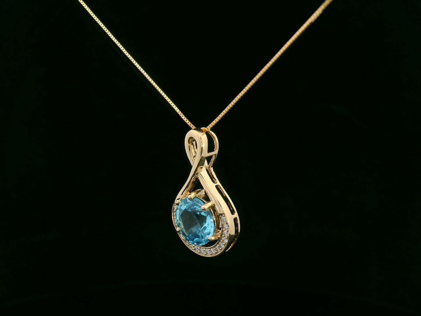 18k yellow gold pendant with 2.30 carat Swiss blue topaz center, diamond halo, and infinity-style bale