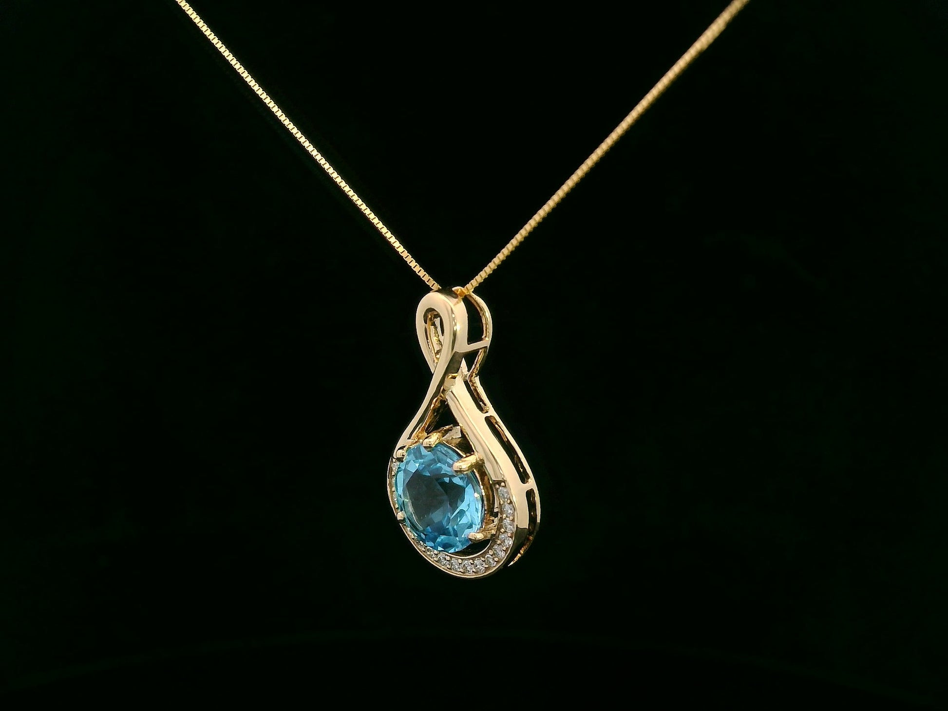 18k yellow gold pendant with 2.30 carat Swiss blue topaz center, diamond halo, and infinity-style bale