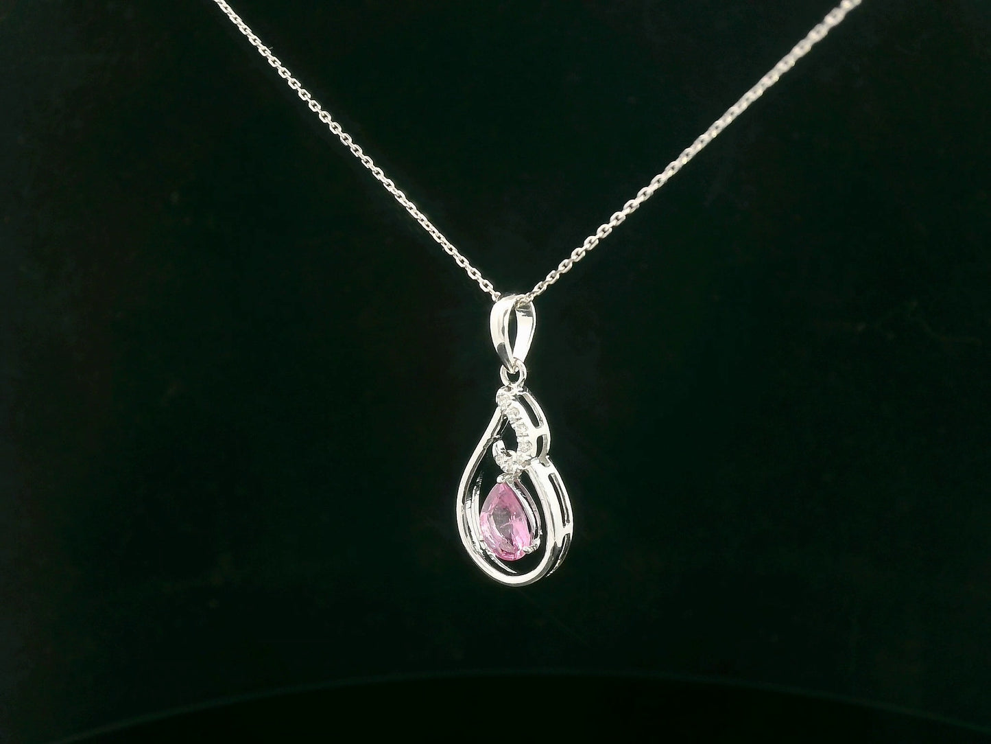 Side profile of pear-shaped pink sapphire pendant with diamond swirl design