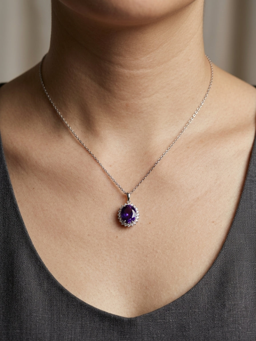Oval purple amethyst pendant surrounded by a sparkling diamond halo in 18K white gold, shown with a chain for display.