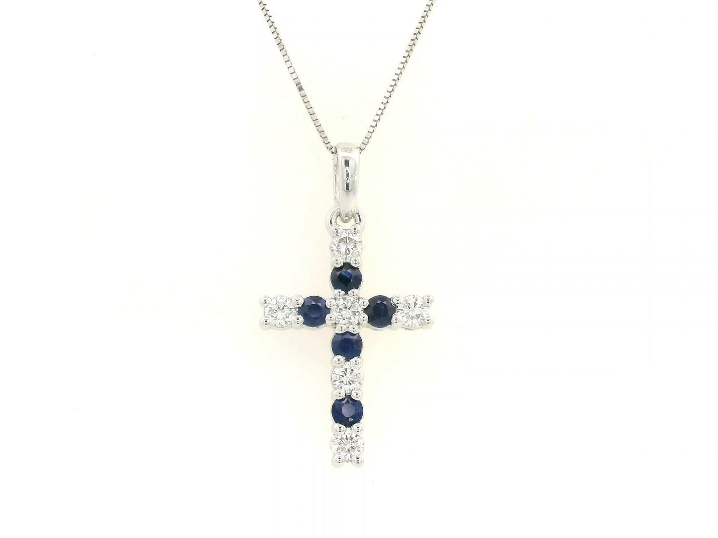 18K white gold diamond and blue sapphire cross pendant with prong-set gemstones by Emirates Diamonds.