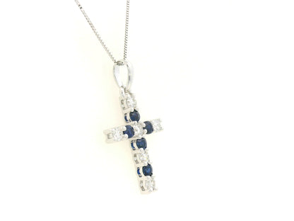 18K white gold diamond and blue sapphire cross pendant with prong-set gemstones by Emirates Diamonds.
