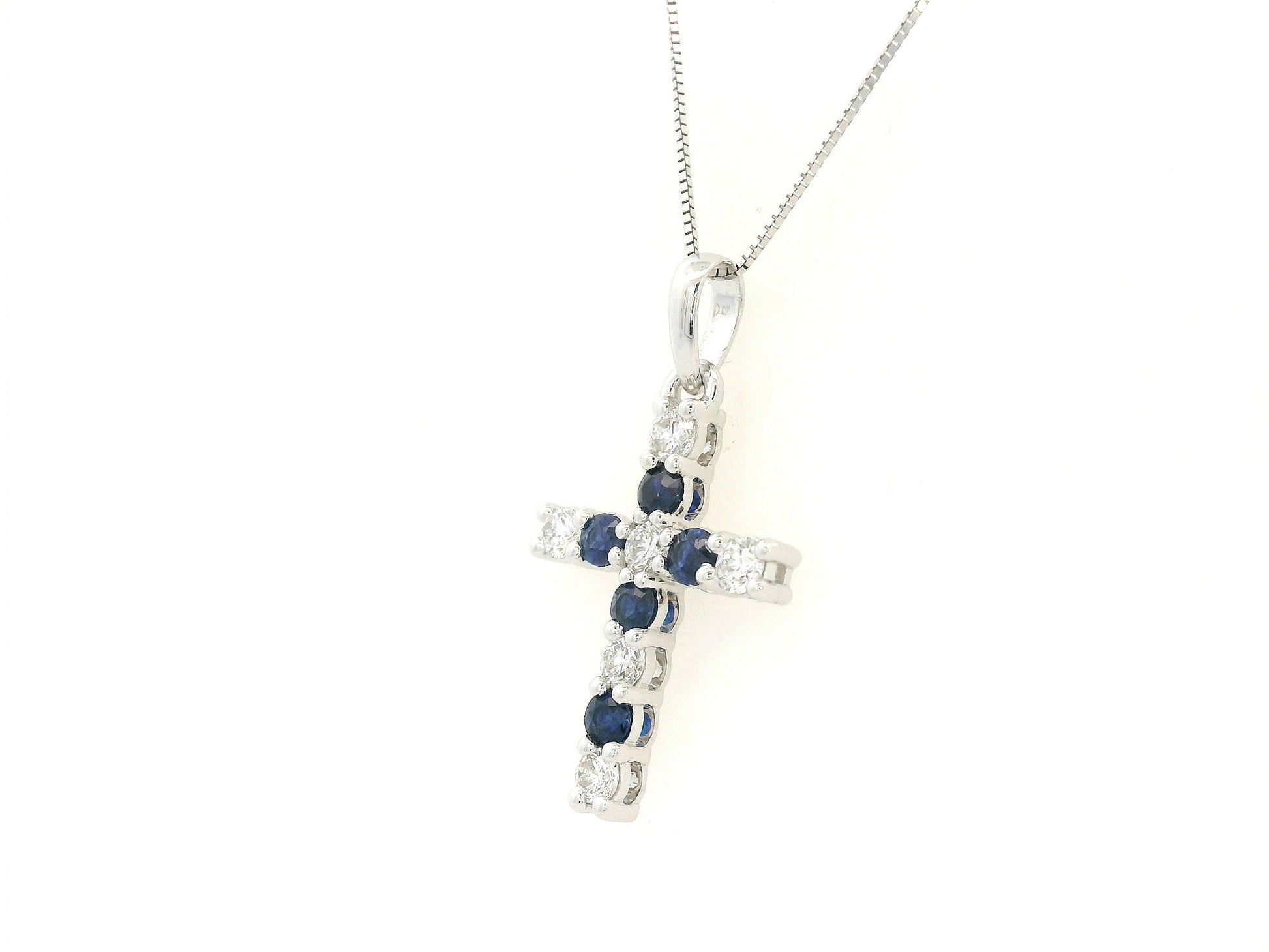 18K white gold diamond and blue sapphire cross pendant with prong-set gemstones by Emirates Diamonds.