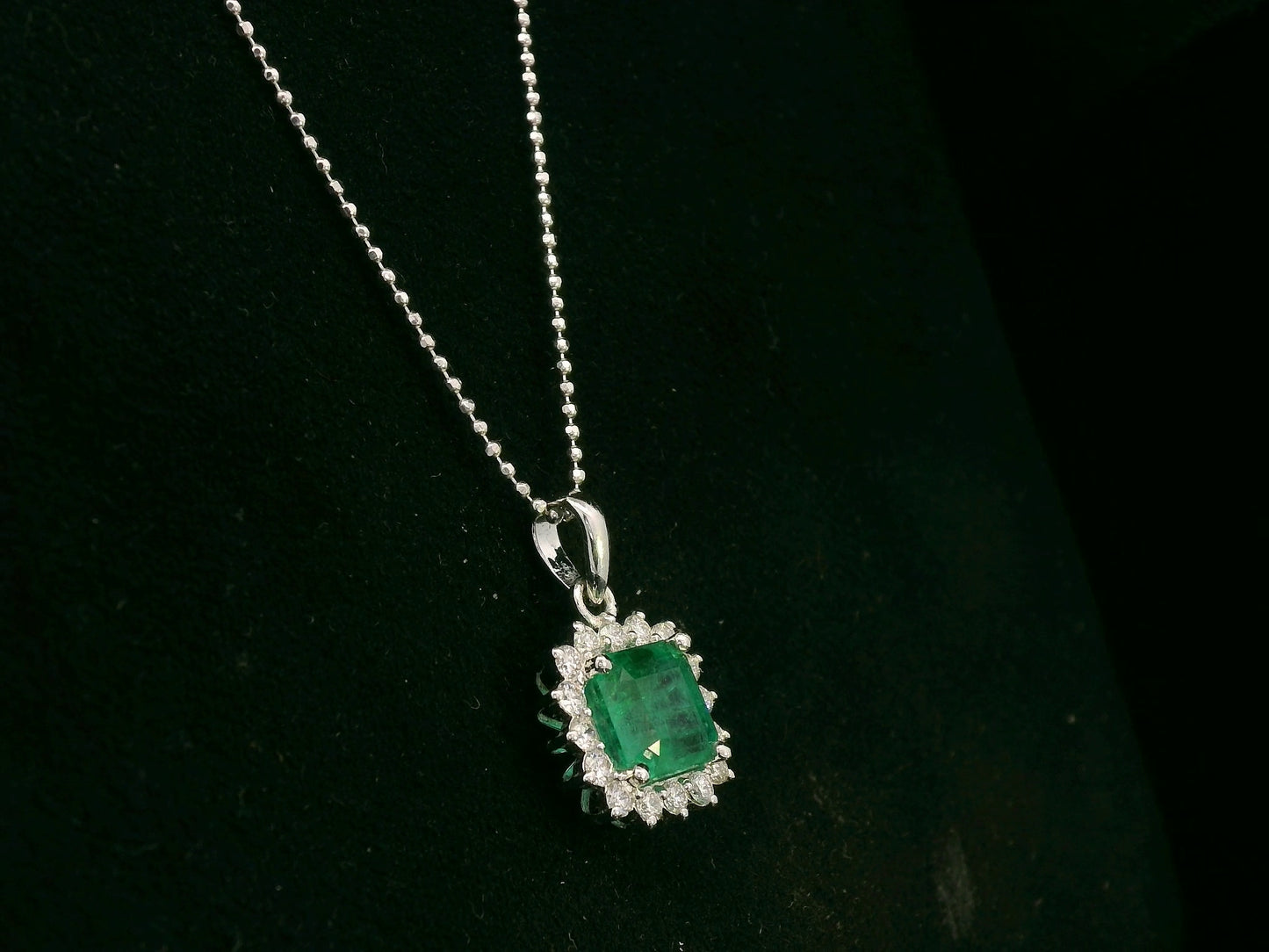 18K white gold emerald and diamond halo pendant by Emirates Diamonds