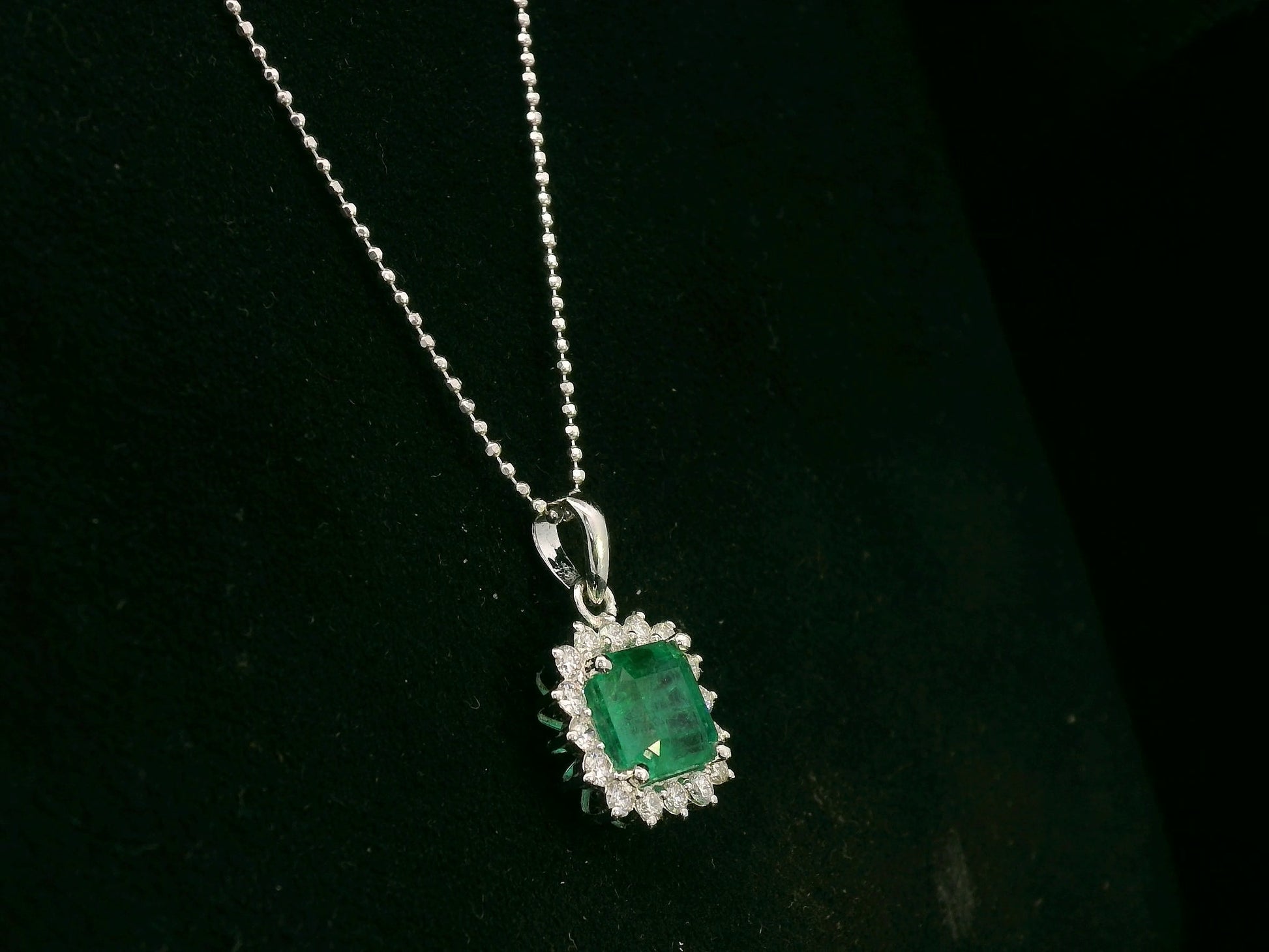 18K white gold emerald and diamond halo pendant by Emirates Diamonds