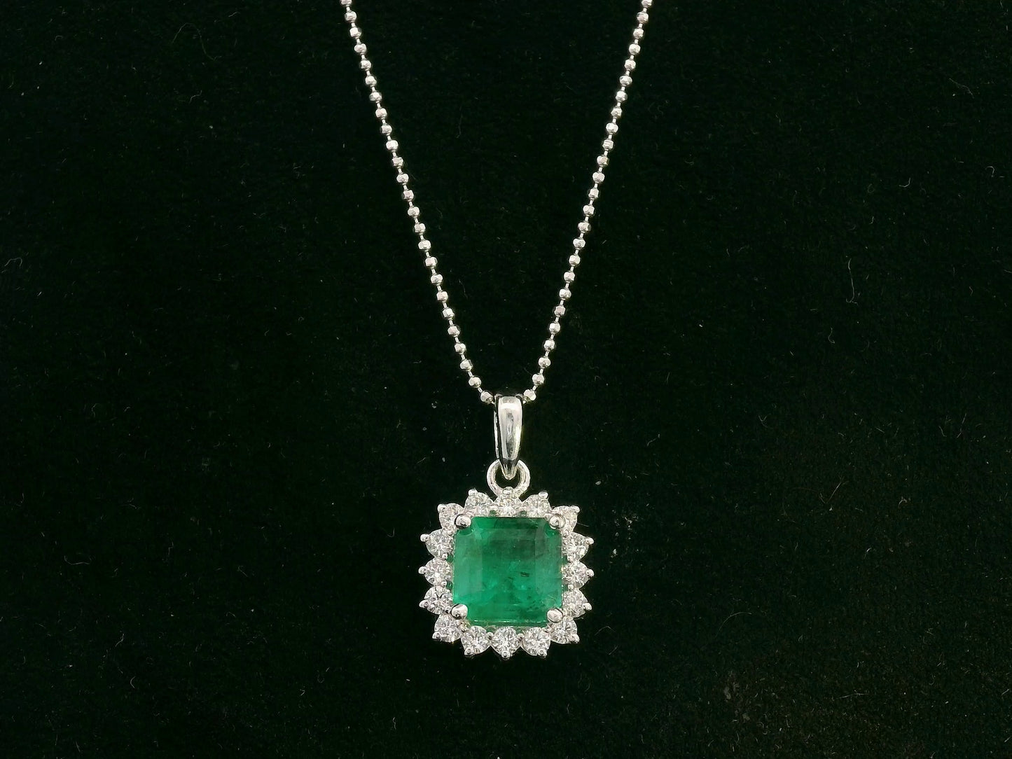 18K white gold emerald and diamond halo pendant by Emirates Diamonds