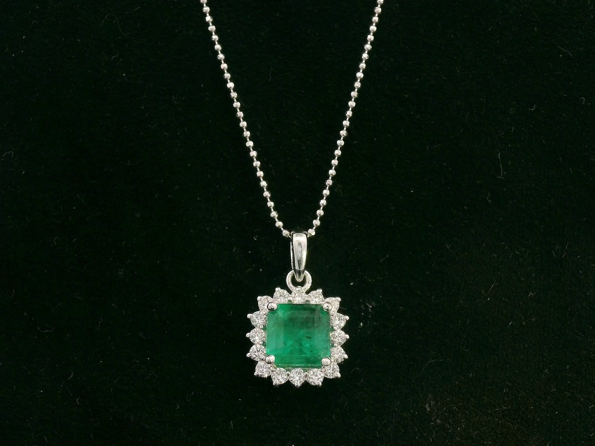 18K white gold emerald and diamond halo pendant by Emirates Diamonds