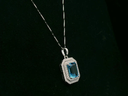 18K white gold Swiss blue topaz and diamond halo pendant with emerald-cut center stone – Emirates Diamonds