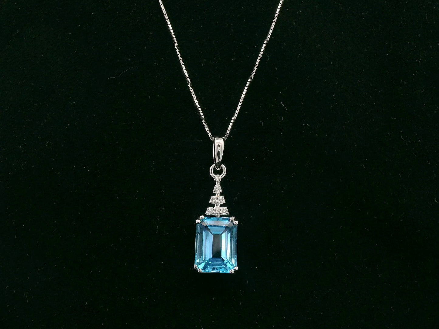 18K white gold Swiss Blue Topaz pendant with emerald-cut blue gemstone and diamond accents by Emirates Diamonds.