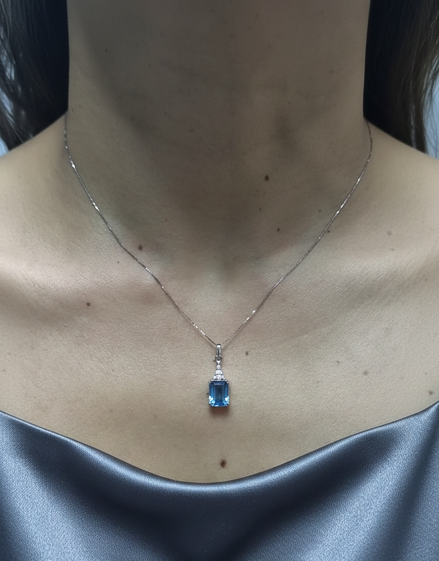 18K white gold Swiss Blue Topaz pendant with emerald-cut blue gemstone and diamond accents by Emirates Diamonds.