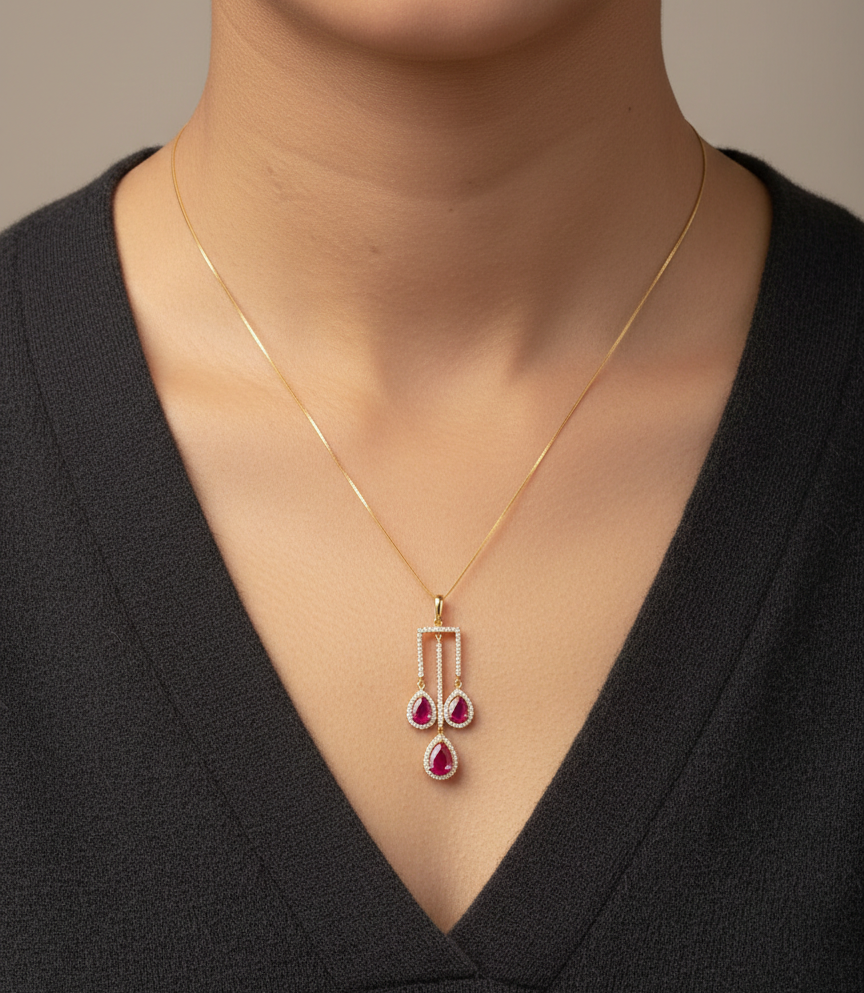 18K yellow gold ruby drop pendant with pear-cut rubies and diamond halo detailing by Emirates Diamonds