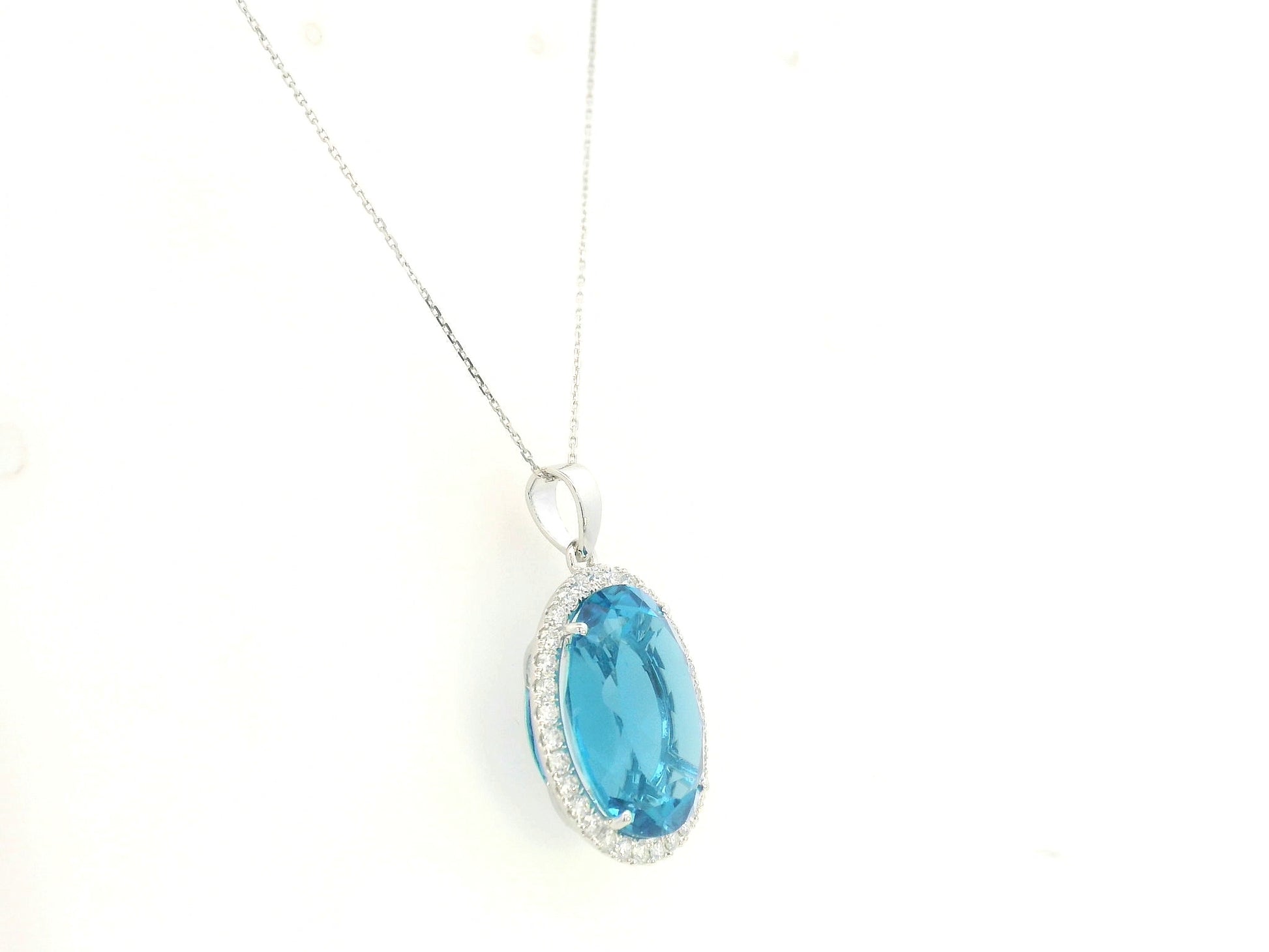 Swiss blue topaz diamond halo pendant in 18K white gold featuring a 21.51 carat oval Swiss blue topaz and 0.76 carats of diamonds by Emirates Diamonds.