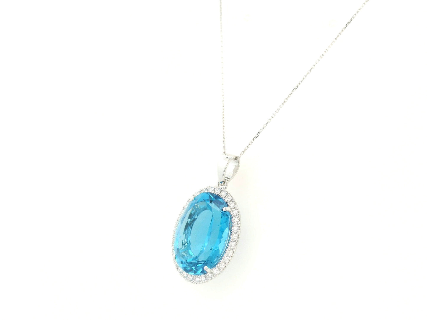 Swiss blue topaz diamond halo pendant in 18K white gold featuring a 21.51 carat oval Swiss blue topaz and 0.76 carats of diamonds by Emirates Diamonds.