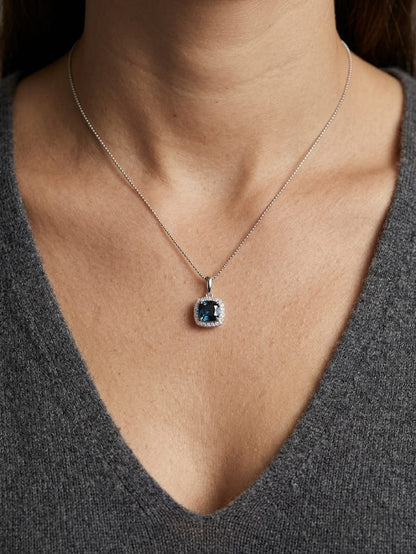 Cushion-cut London Blue Topaz diamond halo pendant in 18K white gold.