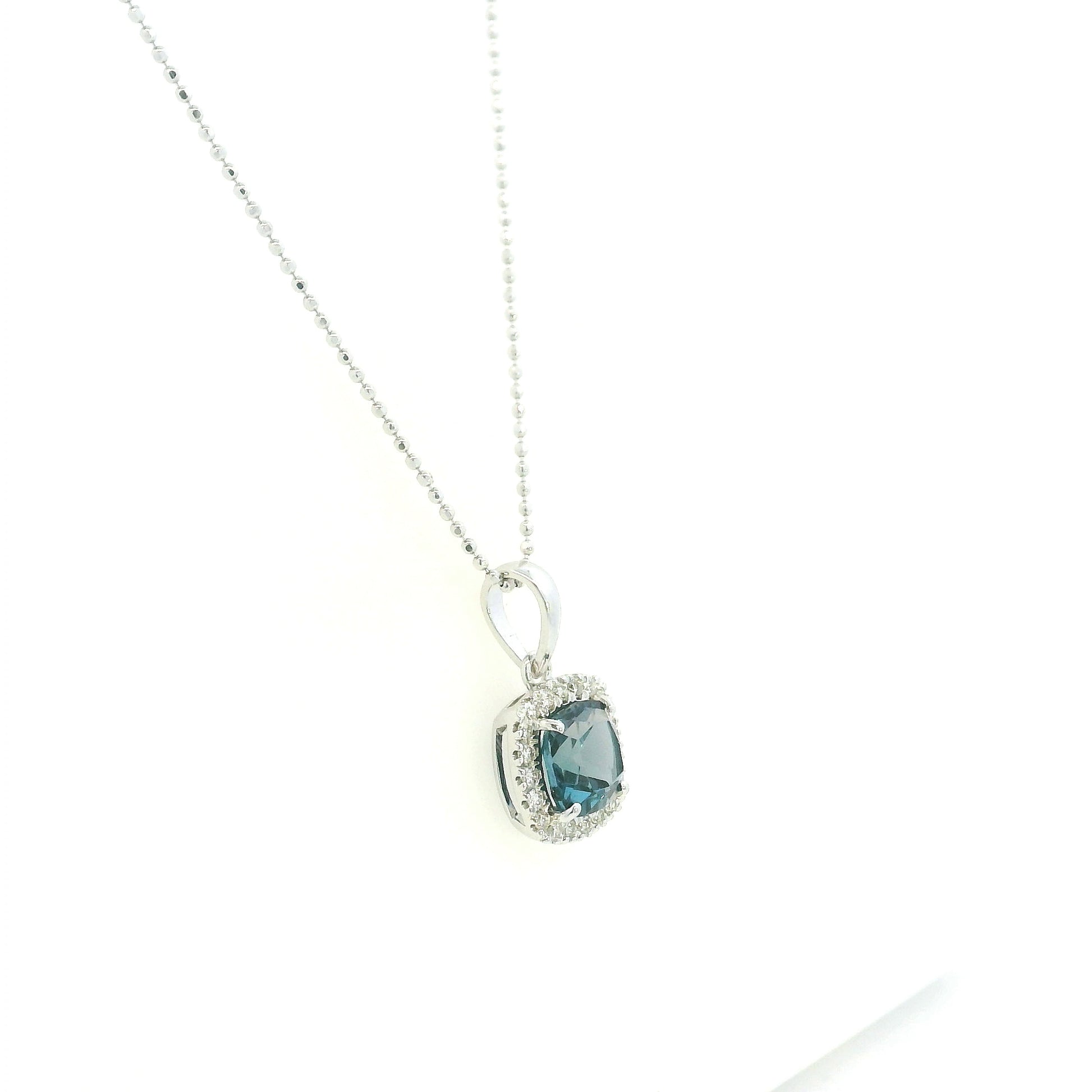 Cushion-cut London Blue Topaz diamond halo pendant in 18K white gold.
