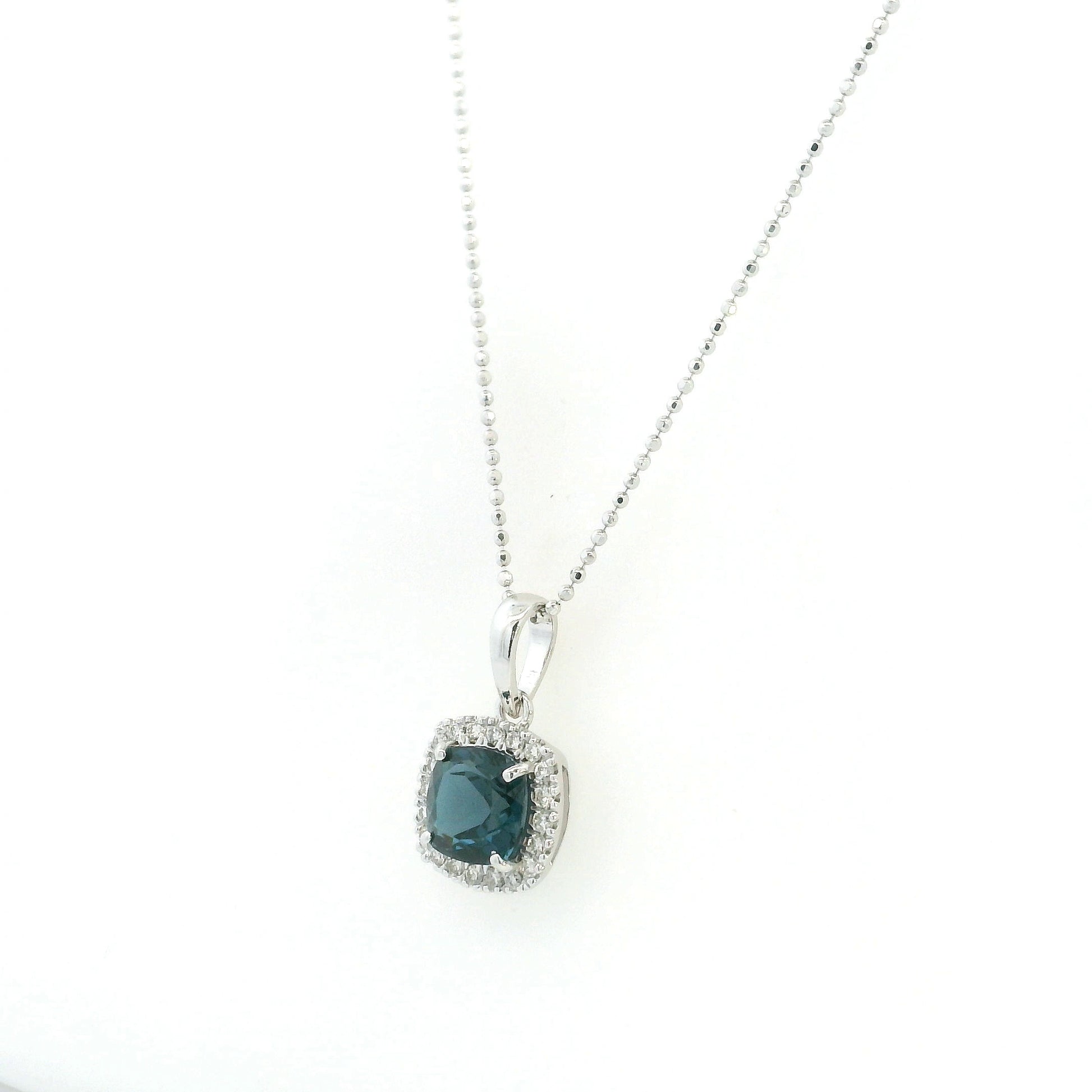 Cushion-cut London Blue Topaz diamond halo pendant in 18K white gold.