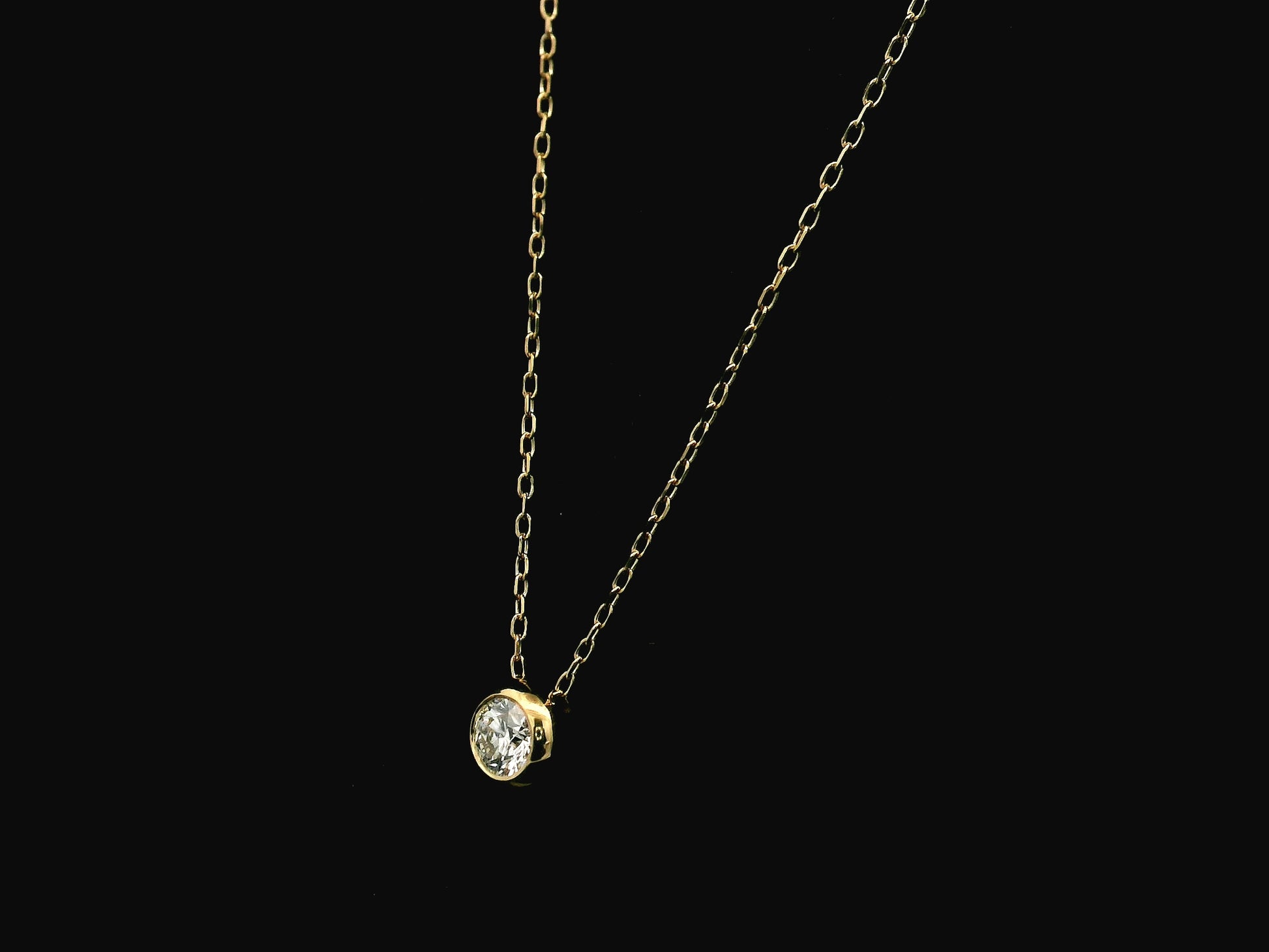 18K yellow gold diamond solitaire necklace featuring a 0.43 carat natural diamond in a modern bezel setting.
