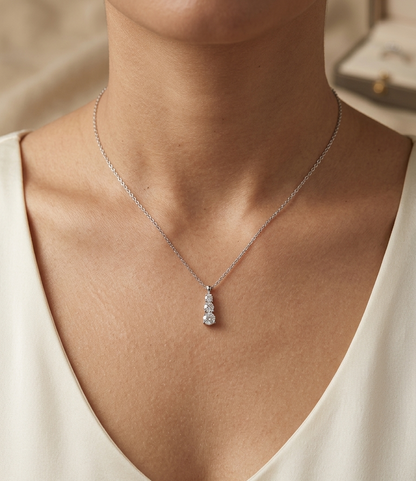 18K white gold three stone natural diamond journey pendant necklace featuring 0.36 carat round brilliant diamonds in a vertical prong setting with matching white gold chain.