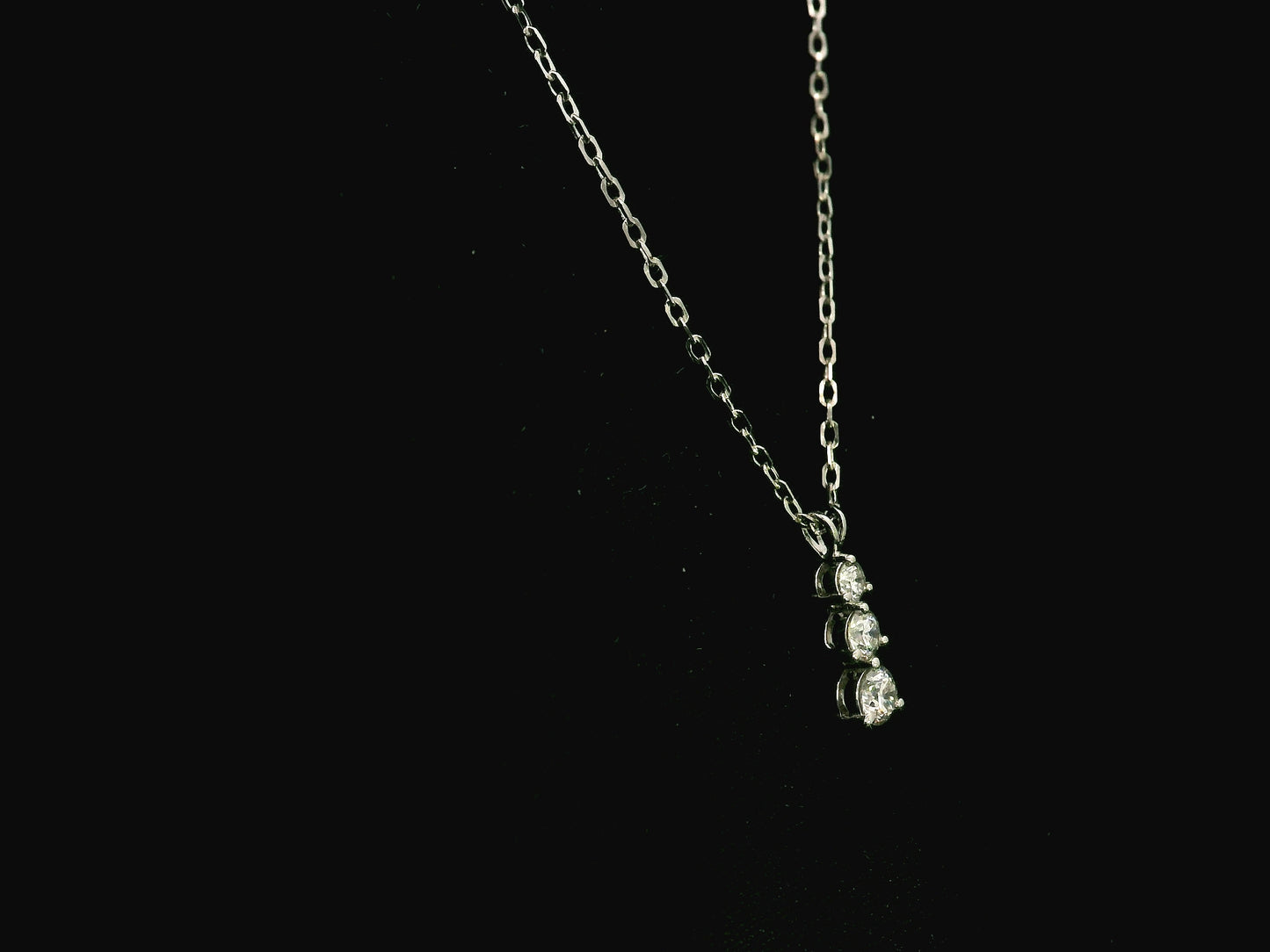 18K white gold three stone natural diamond journey pendant necklace featuring 0.36 carat round brilliant diamonds in a vertical prong setting with matching white gold chain.