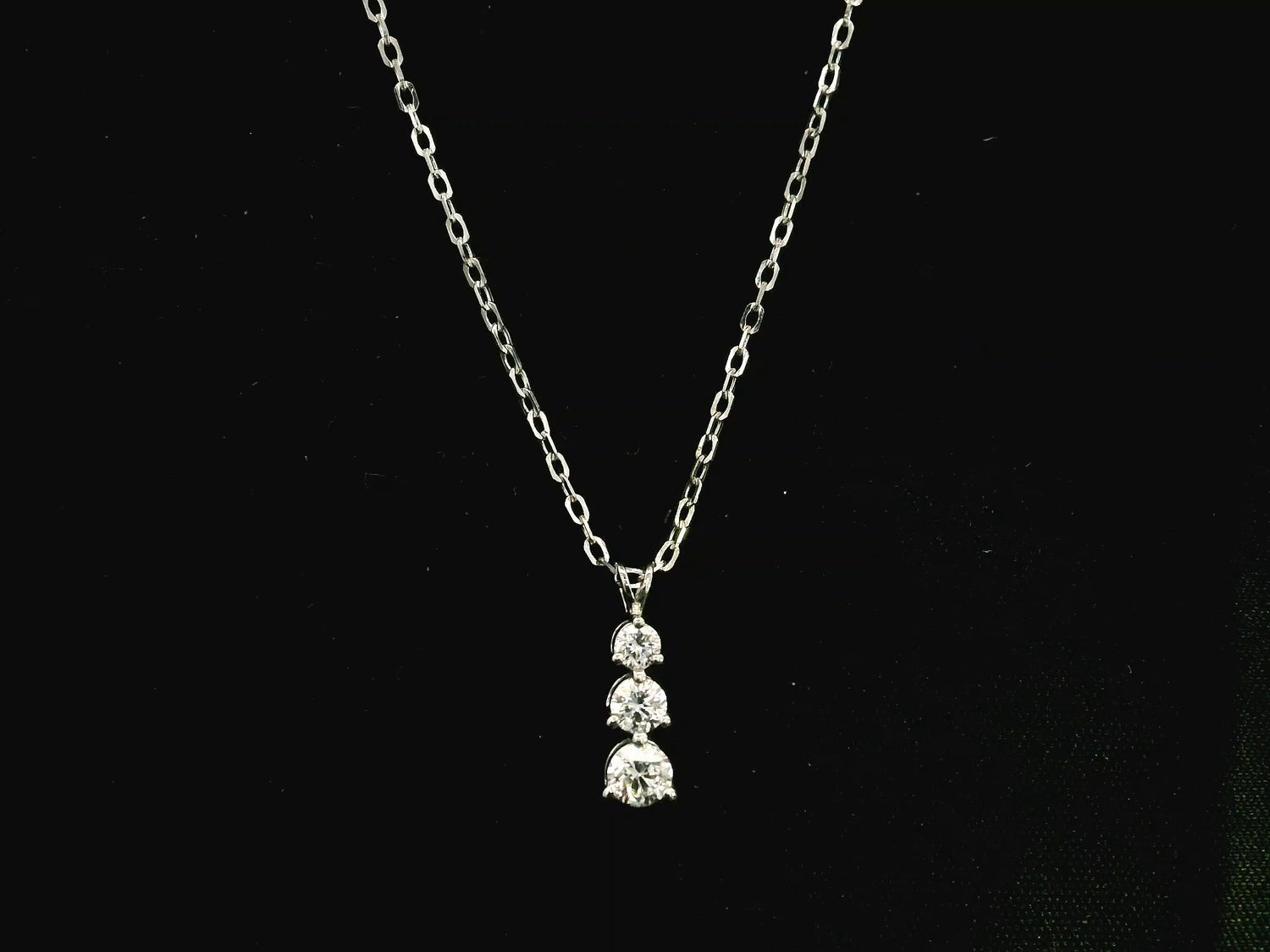 18K white gold three stone natural diamond journey pendant necklace featuring 0.36 carat round brilliant diamonds in a vertical prong setting with matching white gold chain.