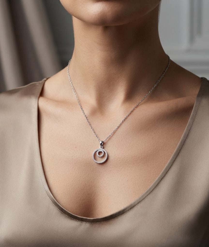 Diamond circle pendant with interlocking open-circle design in 18K white gold, set with round brilliant diamonds.